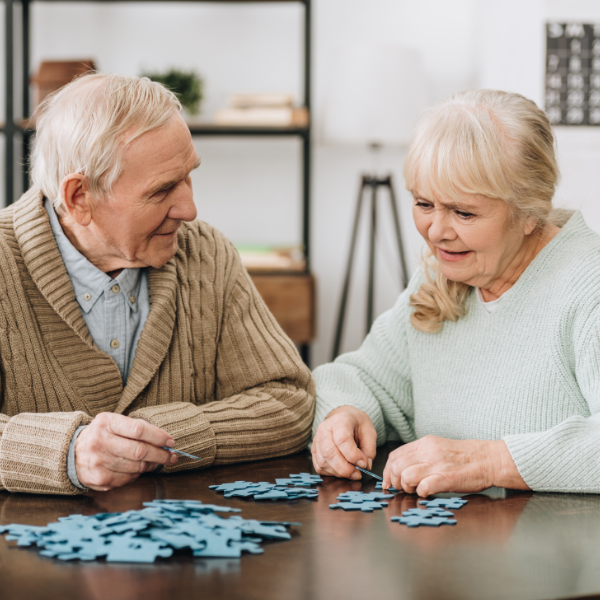 älterer Herr und ältere Frau am Tisch am Puzzle